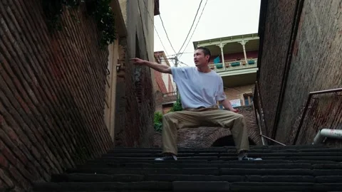 A young guy dances against the background of an authentic city landscape.  Stock Footage 242145848