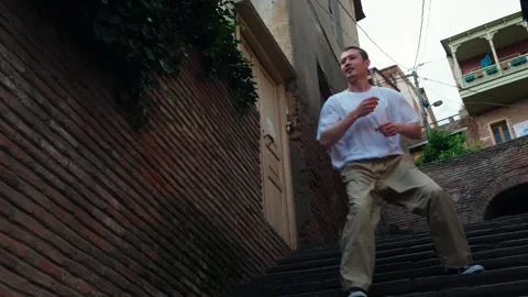 A young guy dances against the background of an authentic city landscape.  Stock Footage 242145906