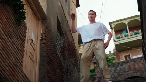A young guy dances against the background of an authentic city landscape.  Stock Footage 242145925