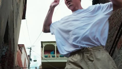 A young guy dances against the background of an authentic city landscape.  Stock Footage 242145944