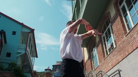 A young guy dances against the background of an authentic city landscape.  Stock Footage 242147745