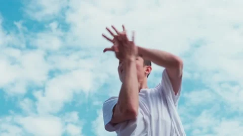 A young guy dances hip-hop while standing on a parapet against the blue sky. Imp Stock Footage 242146185