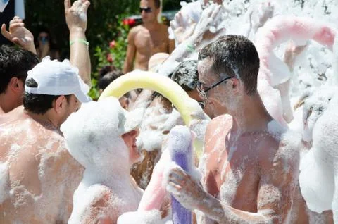 A young guy is dancing on the beach. Foamy party on the sandy beach Fotos Stock