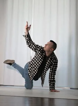 Young guy in a dancing pose on a white background. Modern dance in a plaid .. Foto stock
