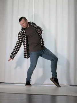 Young guy in a dancing pose on a white background. Modern dance in a plaid .. Foto stock