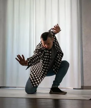 Young guy in a dancing pose on a white background. Modern dance in a plaid .. Stock Photos