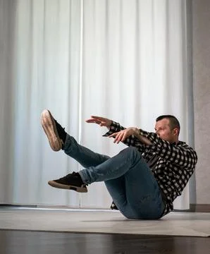 Young guy in a dancing pose on a white background. Modern dance in a plaid .. Stock Photos
