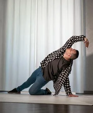 Young guy in a dancing pose on a white background. Modern dance in a plaid .. Stock Photos