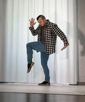 Young guy in a dancing pose on a white background. Modern dance in a plaid .. Stock Photos