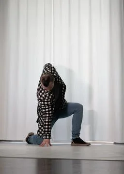 Young guy in a dancing pose on a white background. Modern dance in a plaid .. Stock Photos