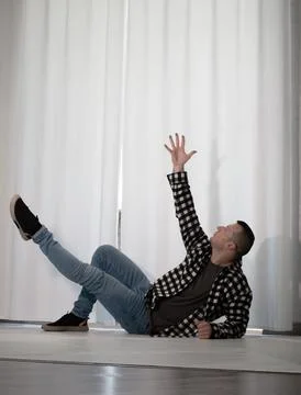 Young guy in a dancing pose on a white background. Modern dance in a plaid .. Stock Photos