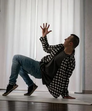 Young guy in a dancing pose on a white background. Modern dance in a plaid .. Stock Photos