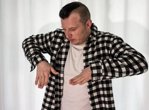 Young guy in a dancing pose on a white background. Modern dance in a plaid .. Stock Photos