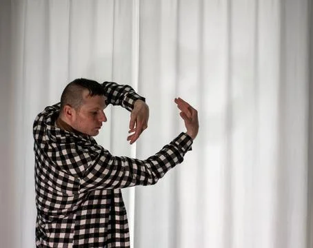 Young guy in a dancing pose on a white background. Modern dance in a plaid .. Stock Photos