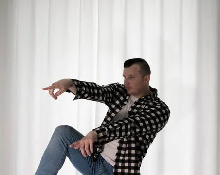Young guy in a dancing pose on a white background. Modern dance in a plaid .. Stock Photos
