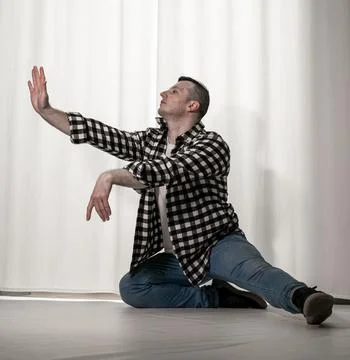 Young guy in a dancing pose on a white background. Modern dance in a plaid .. Stock Photos