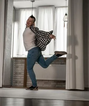 Young guy in a dancing pose on a white background. Modern dance in a plaid .. Photos
