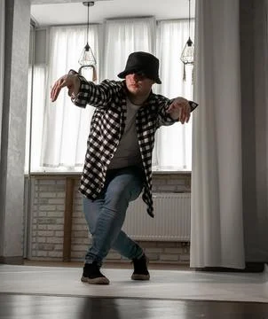 Young guy in a dancing pose on a white background. Modern dance in a plaid .. Stock Photos