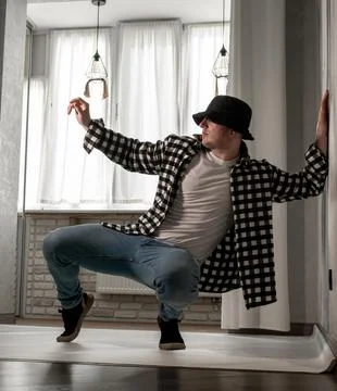 Young guy in a dancing pose on a white background. Modern dance in a plaid .. Stock Photos