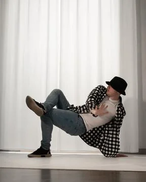 Young guy in a dancing pose on a white background. Modern dance in a plaid .. Stock Photos