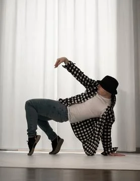 Young guy in a dancing pose on a white background. Modern dance in a plaid .. Stock Photos