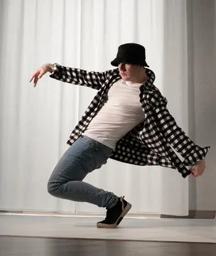 Young guy in a dancing pose on a white background. Modern dance in a plaid .. Stock Photos