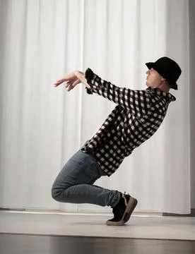 Young guy in a dancing pose on a white background. Modern dance in a plaid .. Stock Photos