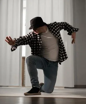 Young guy in a dancing pose on a white background. Modern dance in a plaid .. Stock Photos