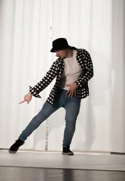 Young guy in a dancing pose on a white background. Modern dance in a plaid .. Stock Photos