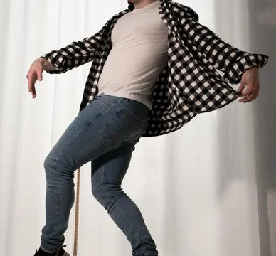 Young guy in a dancing pose on a white background. Modern dance in a plaid .. Stock Photos