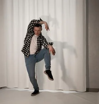 Young guy in a dancing pose on a white background. Modern dance in a plaid .. Stock Photos