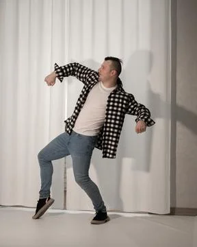 Young guy in a dancing pose on a white background. Modern dance in a plaid .. Stock Photos