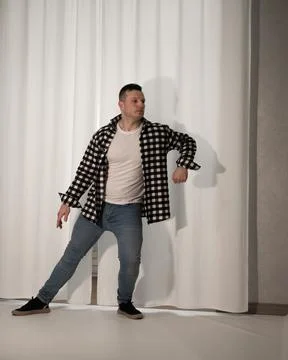Young guy in a dancing pose on a white background. Modern dance in a plaid .. Stock Photos