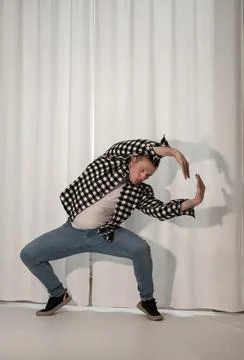 Young guy in a dancing pose on a white background. Modern dance in a plaid .. Stock Photos