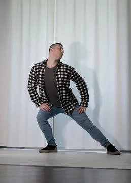 Young guy in a dancing pose on a white background. Modern dance in a plaid .. Stock Photos
