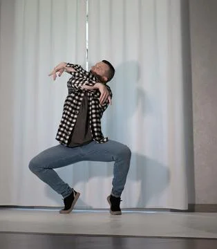Young guy in a dancing pose on a white background. Modern dance in a plaid .. Stock Photos