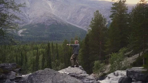 A young guy dancing at the top of a mountain waterfall in the Khibiny Stock Footage 165402935