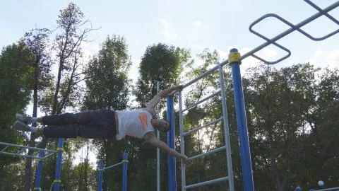 Young guy demonstrates human flag. Athletic man doing gymnastics elements on Stock Photos