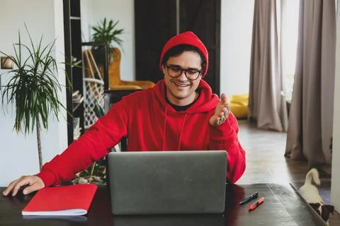 Young guy developer in red clothes working with computer at home office Foto stock