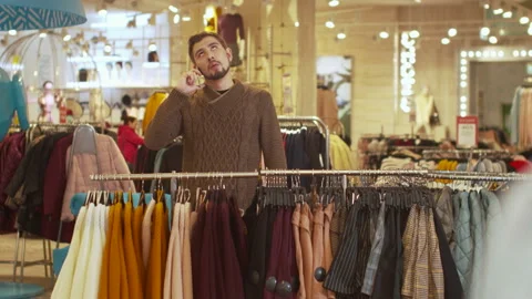 Young guy discusses clothes on the phone in a store Stock Footage 119424729