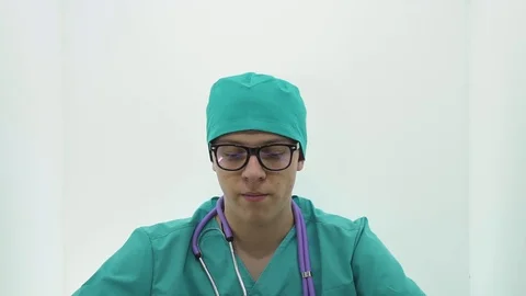 Young guy in a doctor's costume is smiling and working on a laptop Stock Footage 107009010