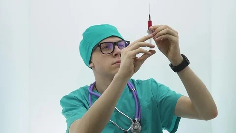A young guy in a doctor's suit raises a syringe with a vaccine Stock Footage 107009022