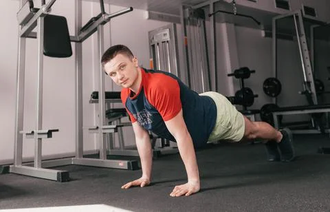 A young guy does push-ups from the floor in the gym during a workout. healthy Stock Photos