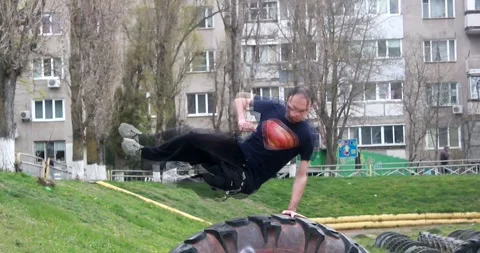 A young guy does a speed vault in parkour style through a large tire Stock Footage 265051284