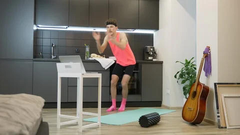 Young guy doing aerobic and fitness exercises at home using online training app Stock Footage 127610986