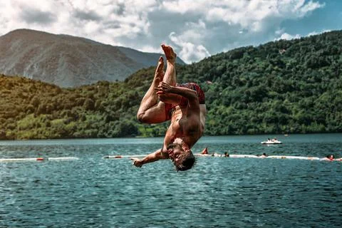 Young guy doing a backflip from a diving board at Perucac lake Stock Photos