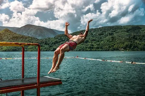 Young guy doing a backflip from a diving board at Perucac lake, Serbia Stock Photos