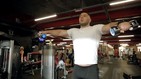Young guy doing dumbbell lateral raise exercise in gym. Stock Footage 85425338