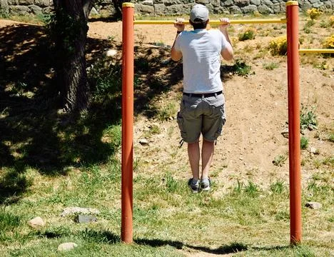 Young guy doing pull-ups on a bar in a park Stock Photos