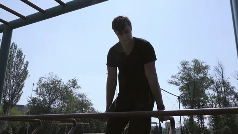 A young guy doing push-UPS on the sports bars on the Playground. Stock Footage 108870396